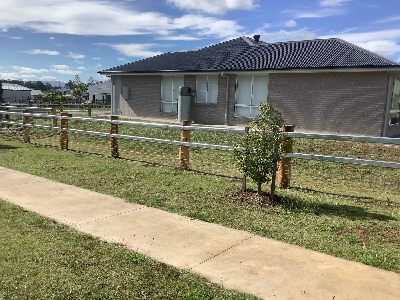 A timber post and rail fence along the front of a brick home