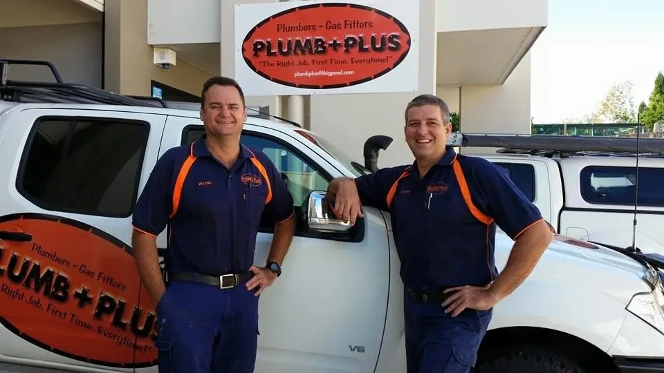 PlumbPlus team members standing beside company vehicles